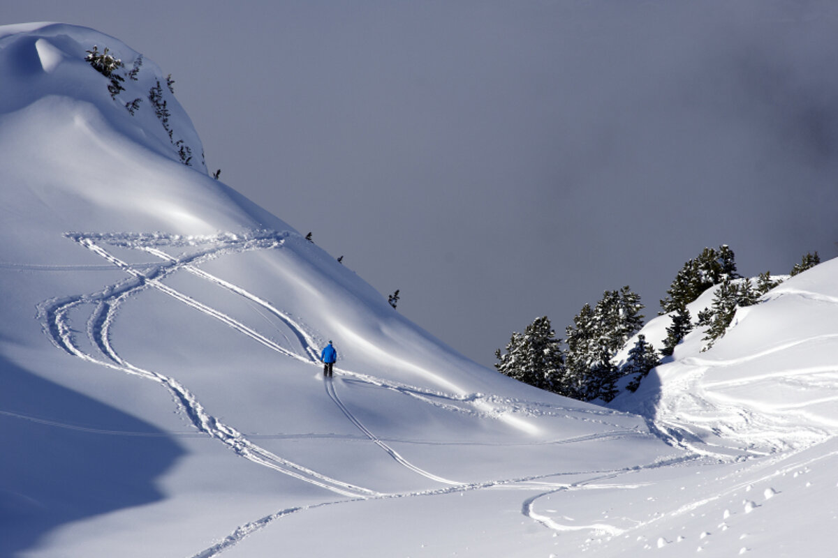 A person in a blue jacket is skiing down a snowy mountain