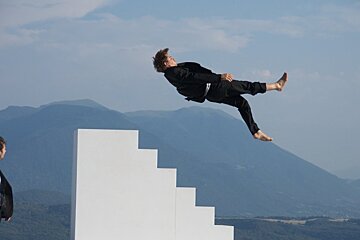 A man in a suit is standing next to a man in a black suit who is flying through the air