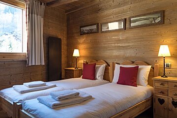 A bedroom with two beds and two lamps