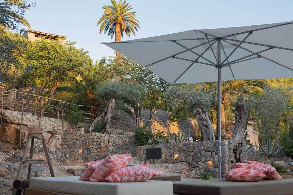 A large white umbrella is sitting under a palm tree