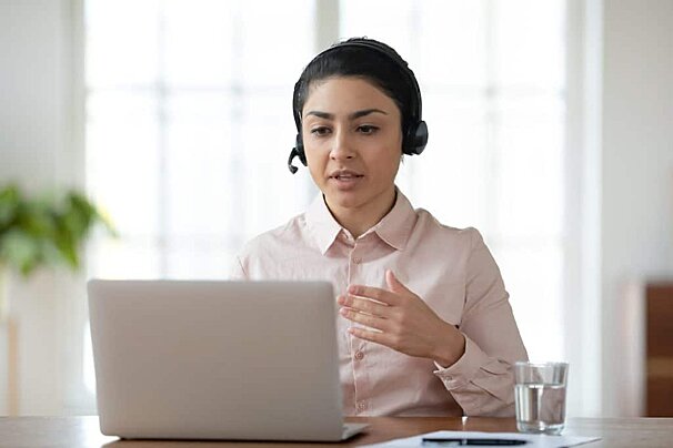 A woman wearing a headset is sitting in front of a laptop computer