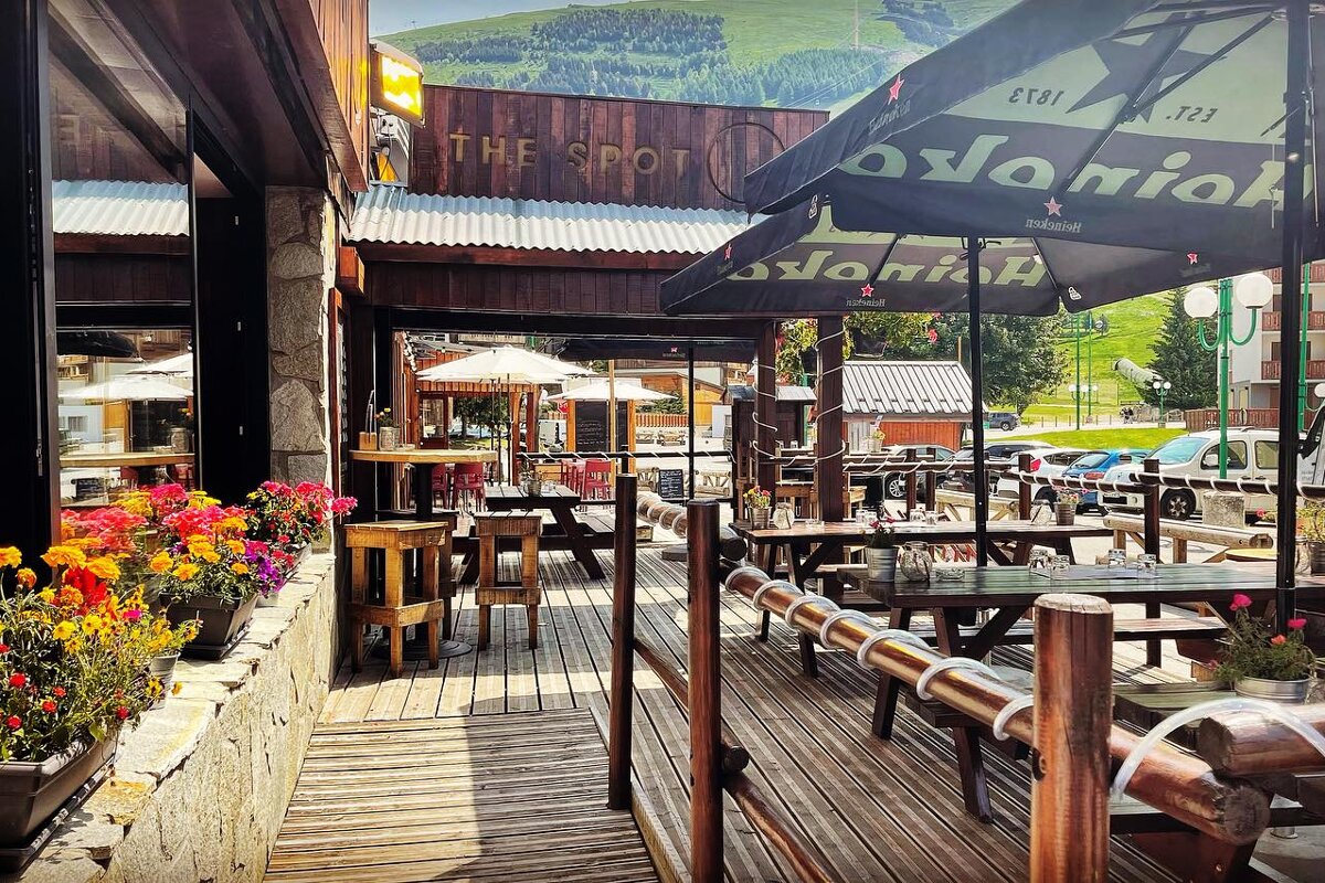 A restaurant called the spot has tables and umbrellas outside