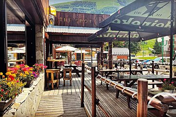 A restaurant called the spot has tables and umbrellas outside