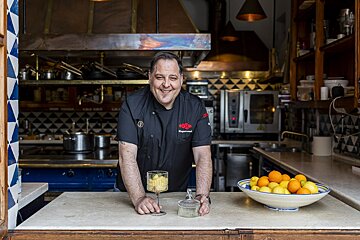 A man in a chef 's uniform stands in a kitchen