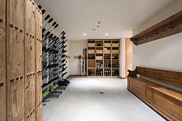 A room with a bench and a rack of skis