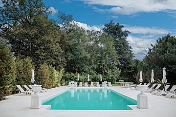 A large swimming pool surrounded by white chairs and umbrellas