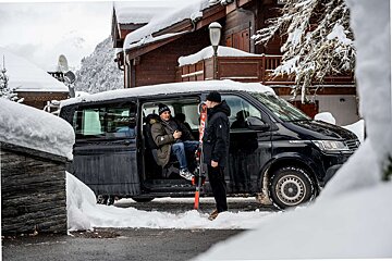 A man with skis standing next to a black van