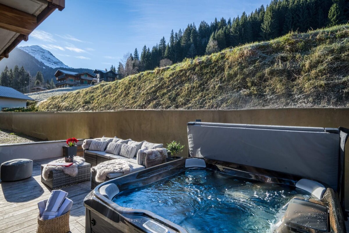 A hot tub on a deck with a mountain in the background