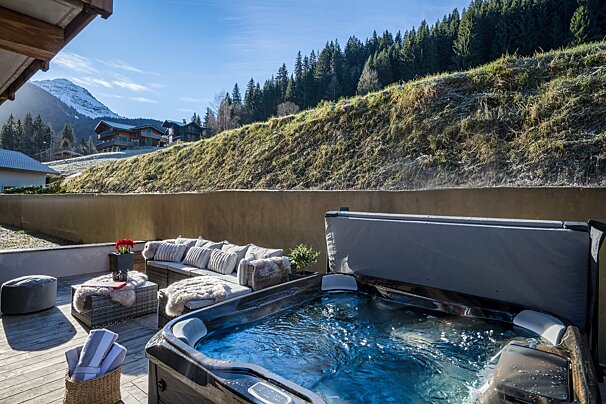 A hot tub on a deck with a mountain in the background