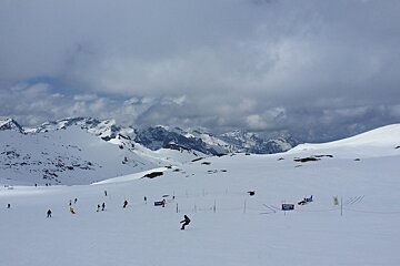 a snowboarder in the distance on a wide piste