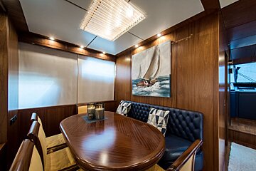 A dining room with a table and chairs and a painting of a sailboat on the wall