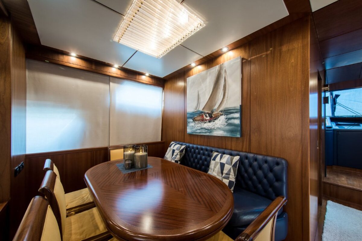 A dining room with a table and chairs and a painting of a sailboat on the wall