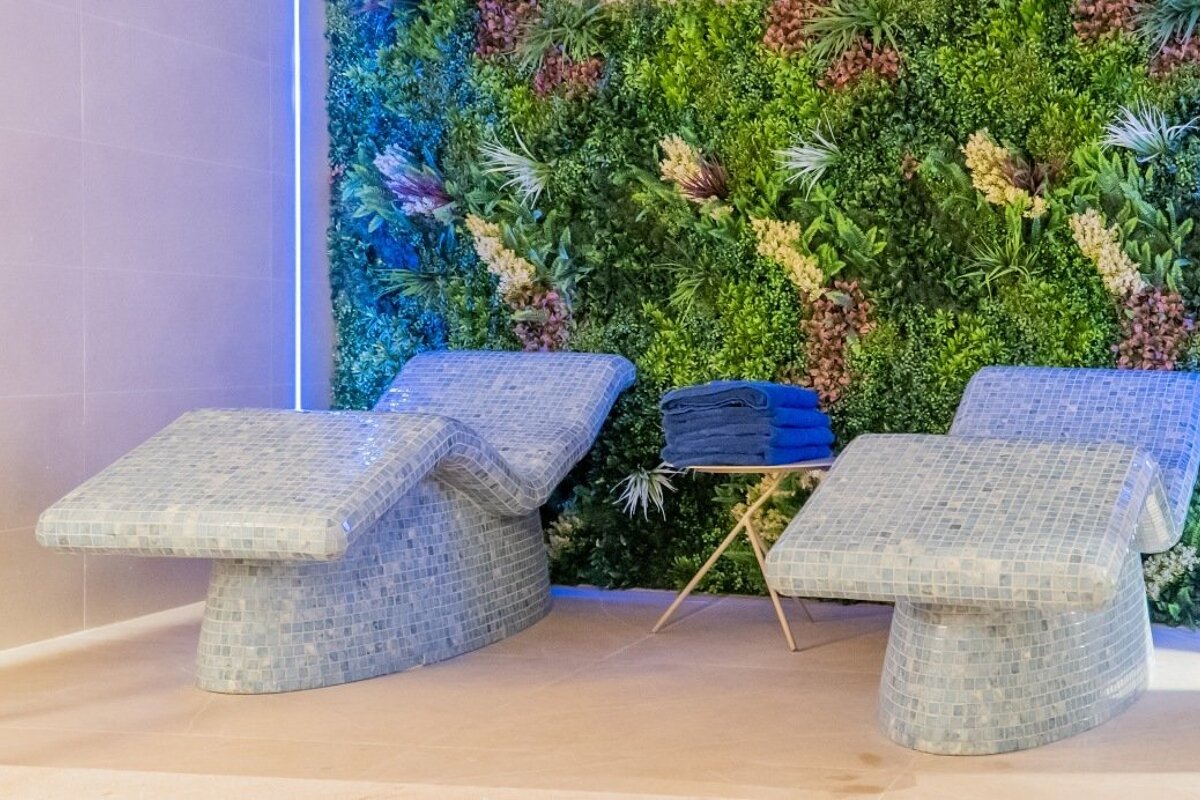 Two lounge chairs with blue towels on them in front of a green wall