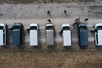 A row of vans are parked on a dirt road