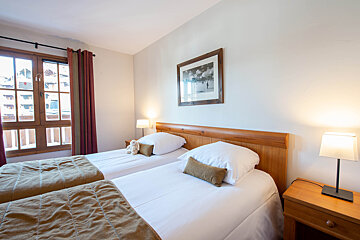 A bedroom with two beds and a picture on the wall