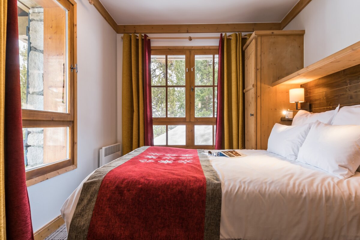 A bed with a red blanket and a book on it