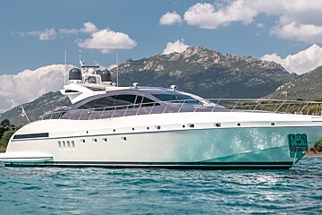 A large white yacht is in the water with mountains in the background