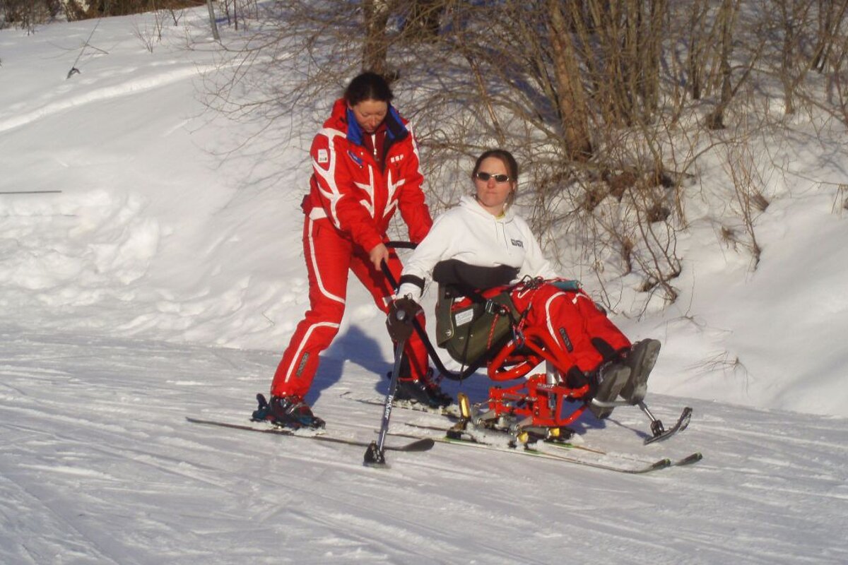 A disabled skier tries assisted skiing in a sitski
