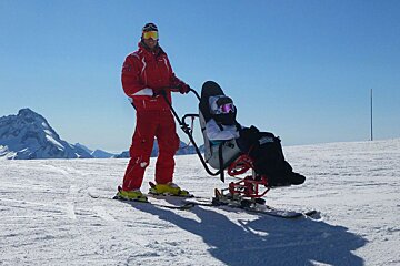 A disabled skier tries assisted skiing in a sitski