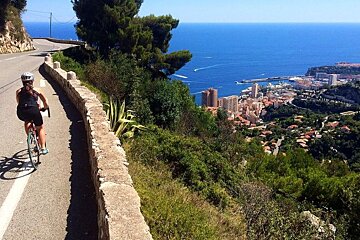 a woman cycling on a road above Monaco