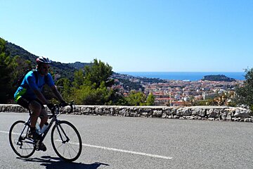 a man cycling on a road above a town in Nice