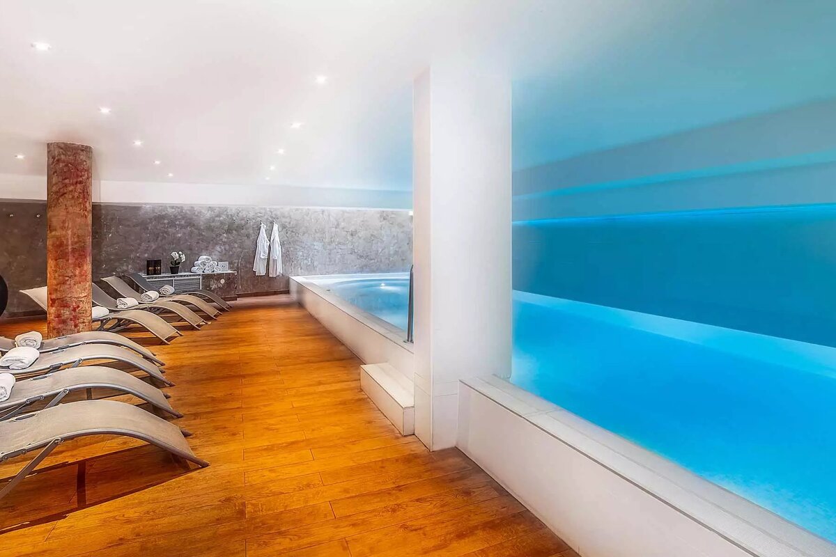 A row of lounge chairs sit next to a large swimming pool