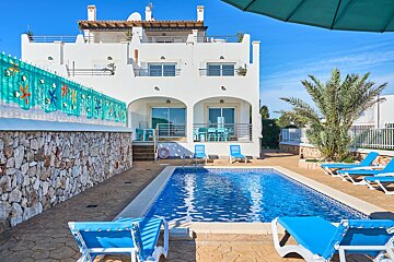 A white house with a swimming pool in front of it