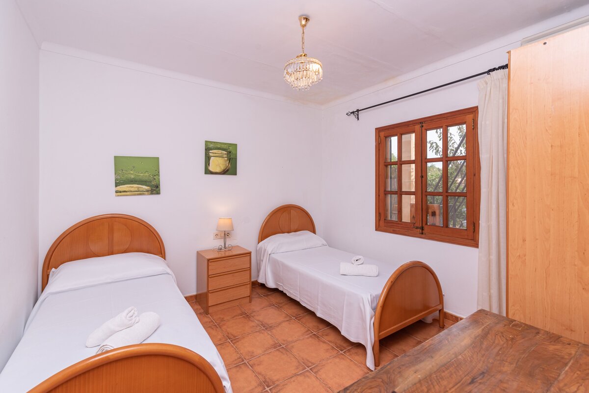 A bedroom with two beds and two paintings on the wall