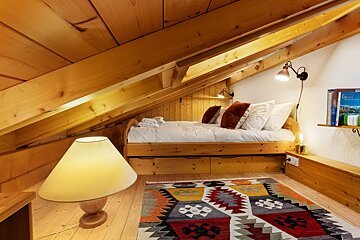 An attic bedroom with a bed and a lamp