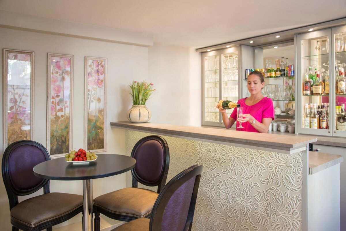 A woman in a pink shirt is pouring champagne into a glass