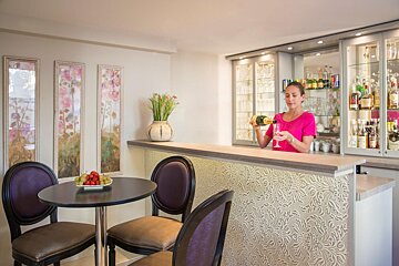 A woman in a pink shirt is pouring champagne into a glass