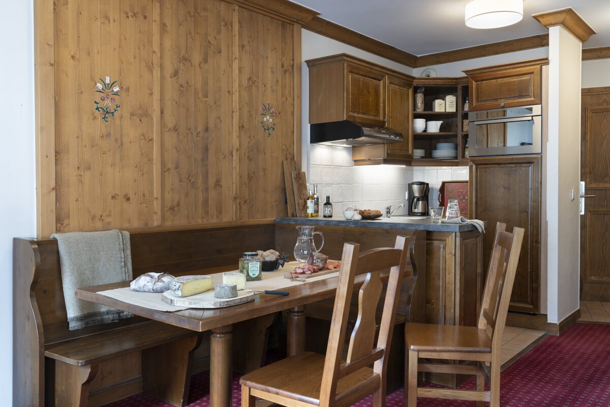 A kitchen with a table and chairs and a pitcher of ketchup