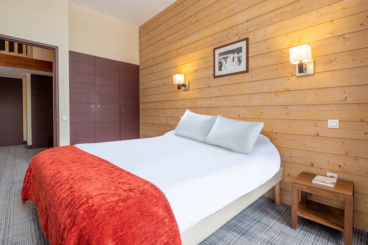 A hotel room with a bed and a nightstand with a book on it
