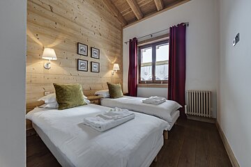 A bedroom with two twin beds and a window