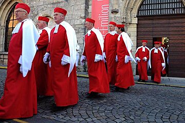 men in red robes coming out of a church