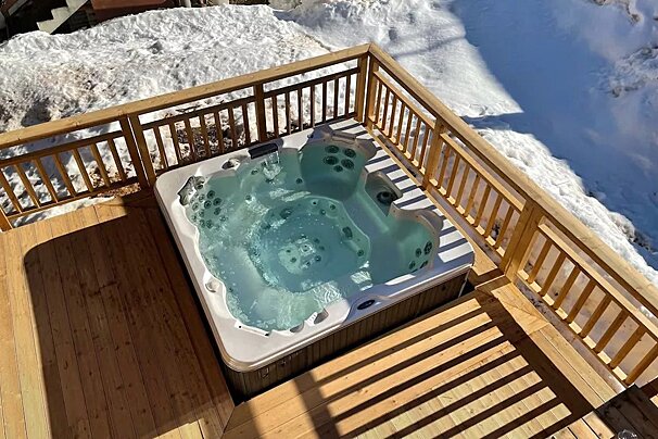 A hot tub on a deck with snow in the background
