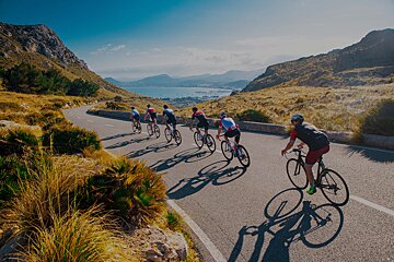 A group of cyclists are riding down a mountain road