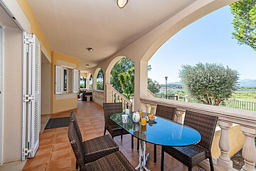 A balcony with a glass table and chairs