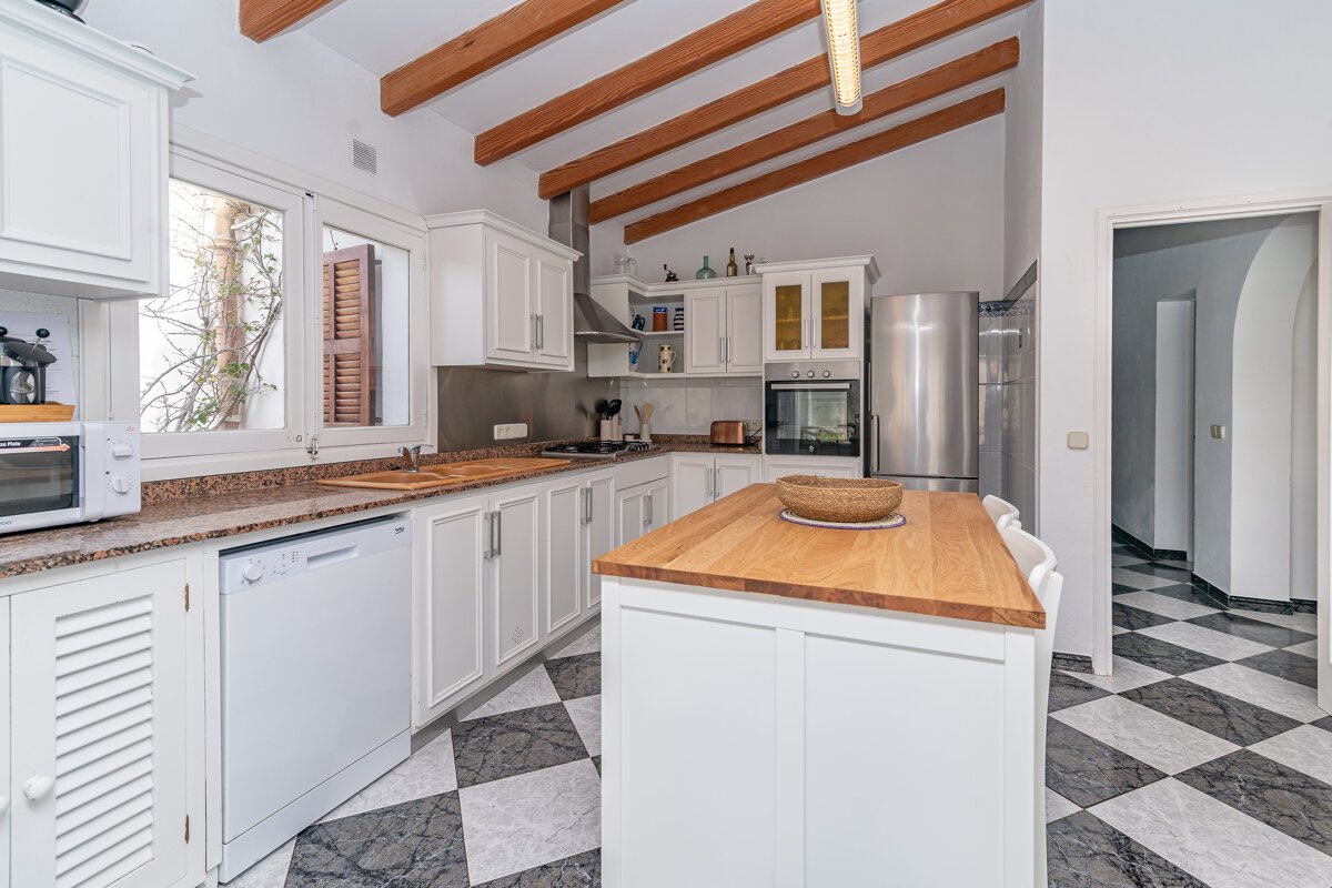 A kitchen with white cabinets and a stainless steel refrigerator