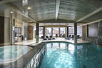 A large indoor swimming pool with a jacuzzi next to it