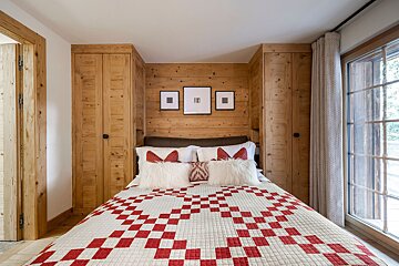 A bed with a red and white checkered blanket and pillows