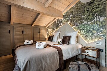 A bedroom with two beds and a wall with trees on it