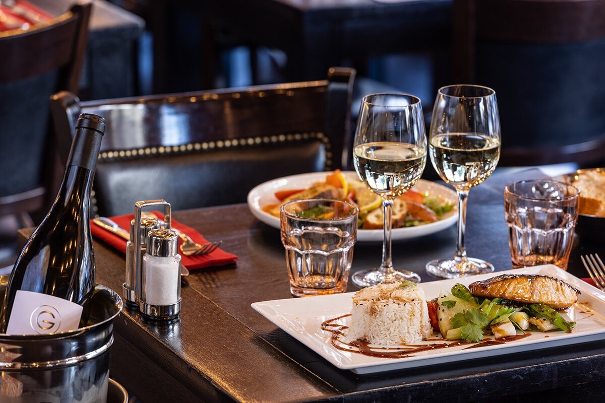 A bottle of wine sits on a table next to a plate of food