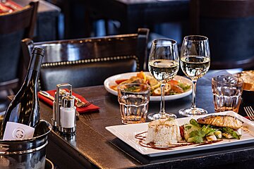 A bottle of wine sits on a table next to a plate of food