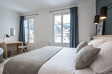 A bedroom with a large bed and a desk