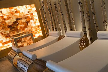 A row of white lounge chairs in a room with trees in the background