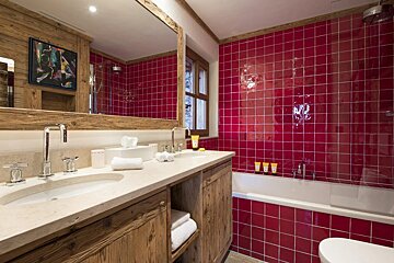 A bathroom with red tiles and wooden cabinets