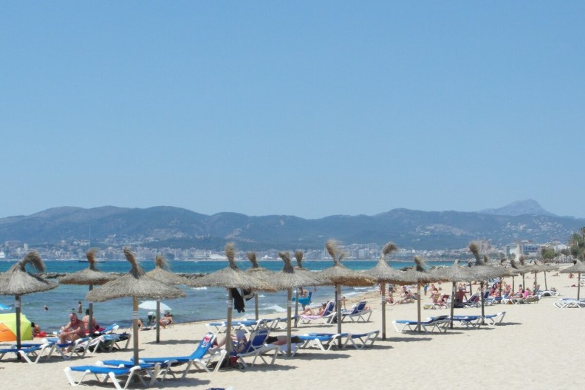 a beach in Mallorca with sea grass parasols