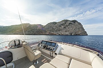 A boat is in the ocean with mountains in the background