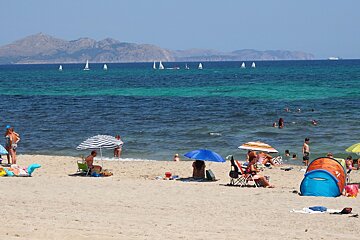 a beach with yachts out at sea